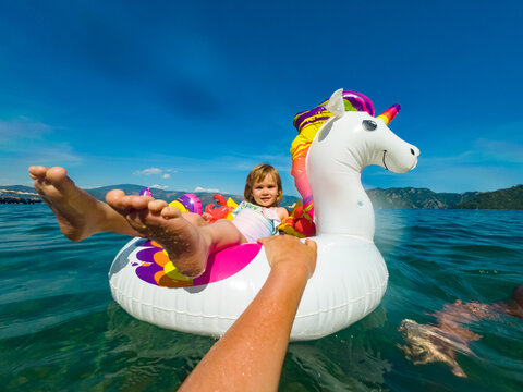 child  rides on inflatable ring by sea