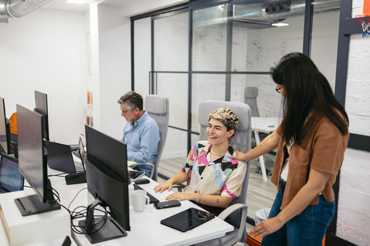 Non-binary person working in a modern office talking to their boss