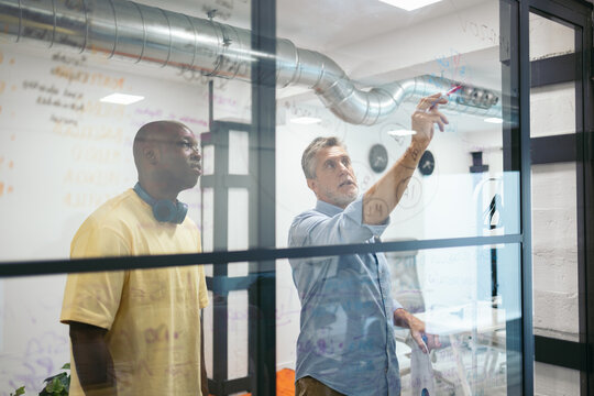 Businessmen designing a work project writing on a glass in the office