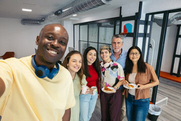 Selfie of diverse team of workers having fun at office party