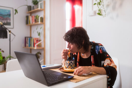 Woman having breakfast in front of computer