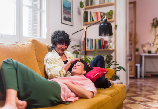 Mother caressing adult daughter on home sofa