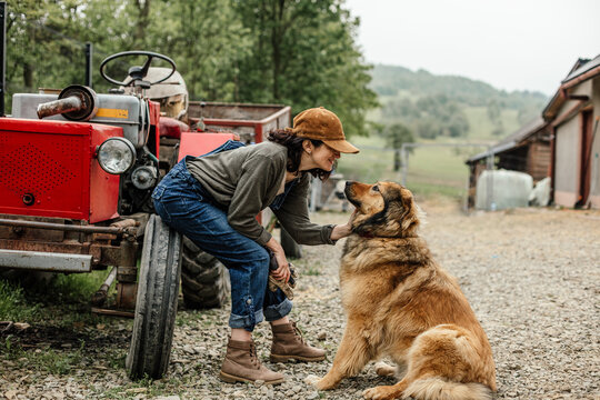 An attractive girl on her farm looks at her big cute dog