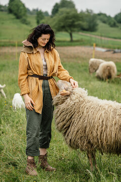 A beautiful farmer woman strokes her sheep in the field