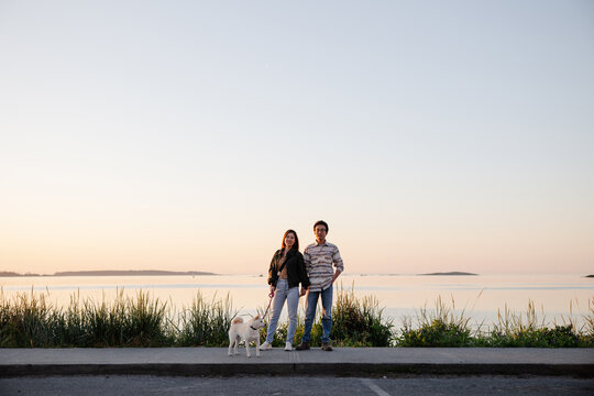 Happy couple with pet outside at sunset together.