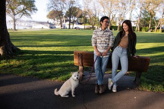 Young couple out walking their dog together in the park.