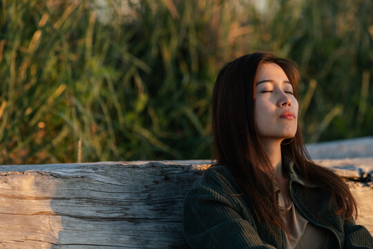 Serious and meditating woman outside on the beach alone.