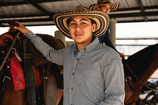 Smiling young man holding his horse in a rural area of Colombia