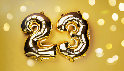 Banner with number 23 golden balloons with copy space. Twenty-three years anniversary celebration concept on a yellow background with shiny bokeh.