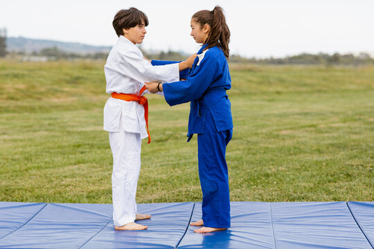 Judokas practicing judo facing each other outdoors
