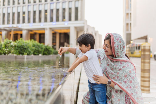 Mother with son playing in fountain
