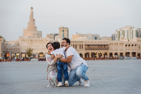 Happy Indian parents hugging son in city