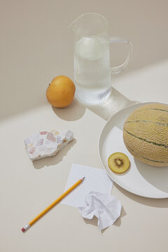 Tranquil Still Life: Water, Fruit, and Terrazzo on Beige Surface