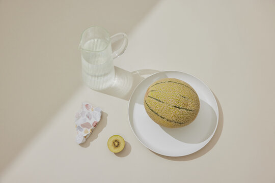 Tranquil Still Life: Water, Fruit, and Terrazzo on Beige Surface