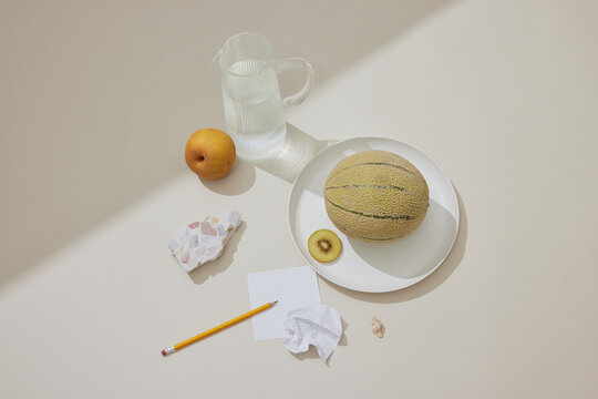 Tranquil Still Life: Water, Fruit, and Terrazzo on Beige Surface