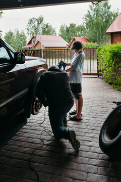 Teen boy helps dad repair automobile.