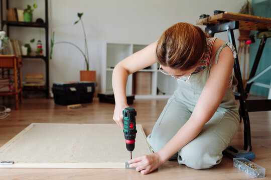 A woman screws a hinge in the door