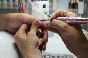 Girl brushes nails with a professional machine