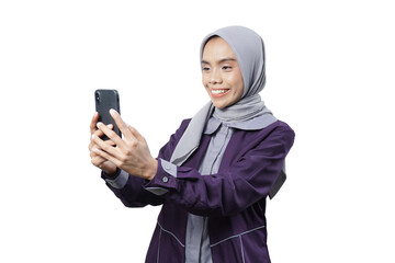 Cheerful beautiful Asian woman in casual shirt and hijab using a mobile phone