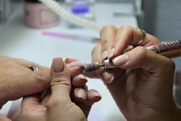 Girl brushes nails with a professional machine