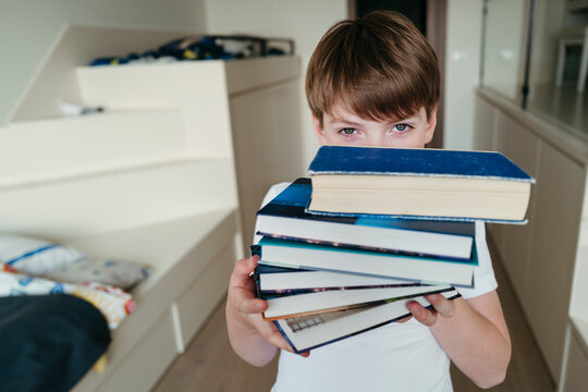 Young boy with stack of books.