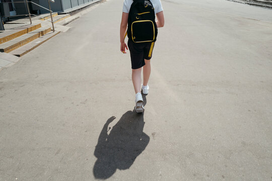 Unrecognizable student with backpack goes to school.