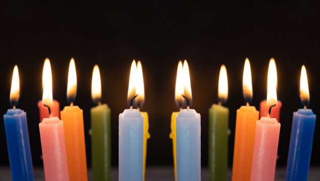 Group of colorful candles burning in the dark