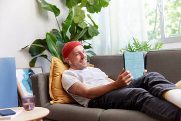 Casual man resting with tablet on couch