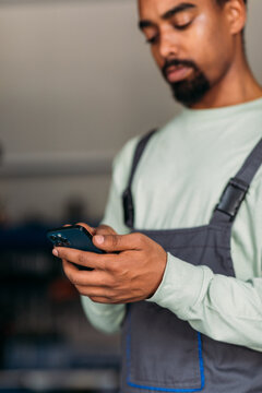 Mechanic in Car Workshop Using Phone