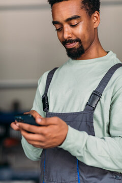 Mechanic in Car Workshop Using Phone