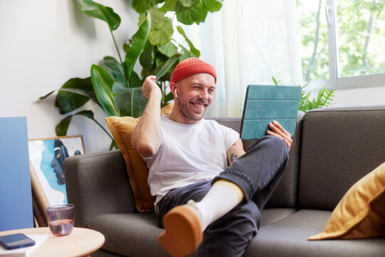 Happy man chatting online while resting on couch