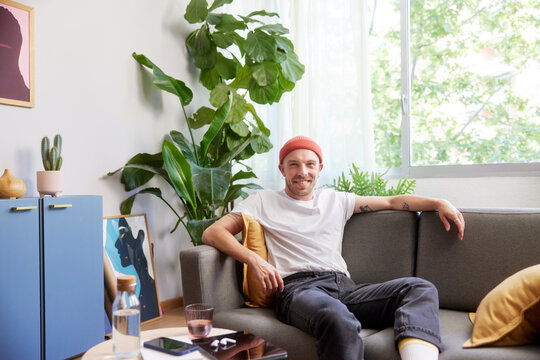 Smiling hipster guy resting on sofa