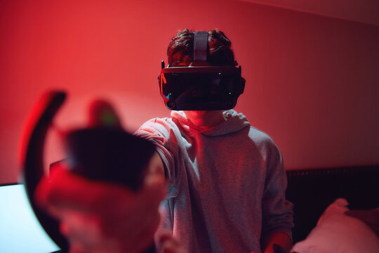Young man wearing a VR headset immersed in playing video game