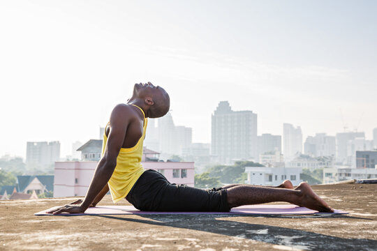 Man practicing bhujangasana or cobra pose on yoga mat 