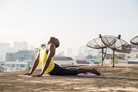 Man practicing bhujangasana or cobra pose on yoga mat 