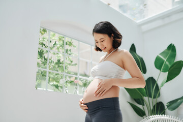 pregnant woman touch her belly in living room