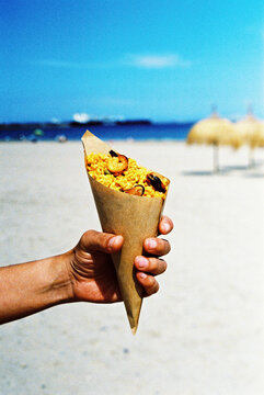 man holding a paper cone with paella, 35 mm film