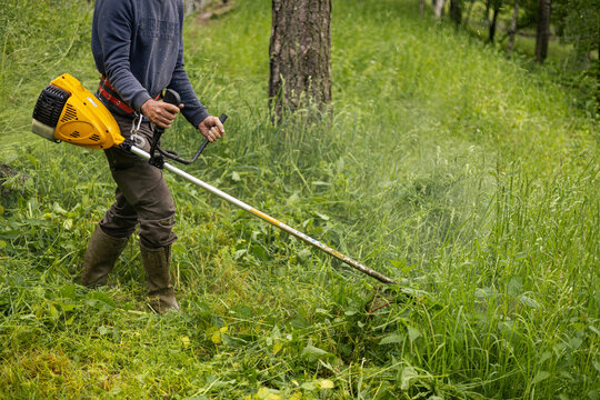 Man cuts weeds with a trimmer