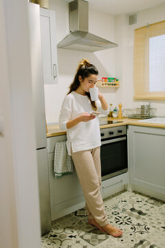 A woman has a coffee in her kitchen