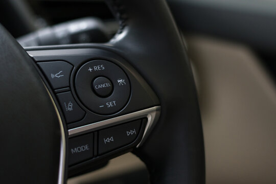 steering wheel buttons for cruise control functions, automatic speed limiter in modern car, shallow depth of field