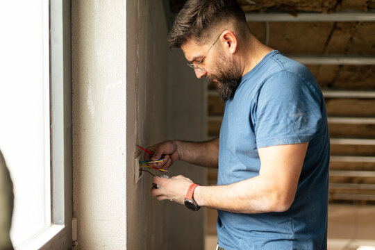Portrait of an electrician connects the wires