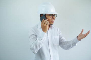 young Asian male engineer wearing white hard hat was talking on a cell phone for construction work isolated on white background, copy space.