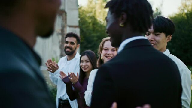 The groom walks past the applauding guests to the church at an outdoor wedding