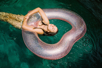 Woman swimming with heart-shaped  swim ring in the pool