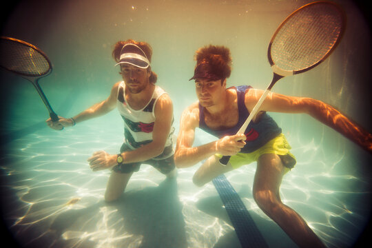 Funny summer portrait of friends playing badminton underwater