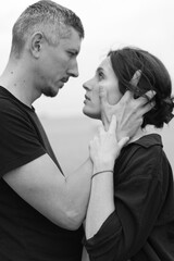A young couple of beautiful people have fun in the field near round bales of dry hay