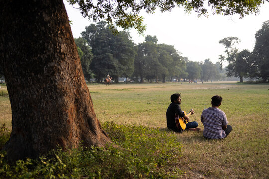 Two friends enjoy music sitting at the greenfield 