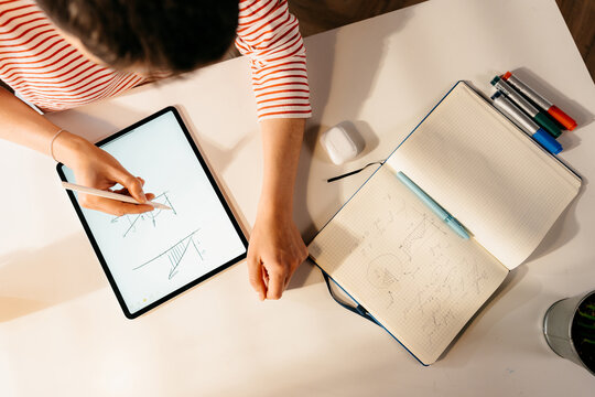 A woman draws graphs on a tablet