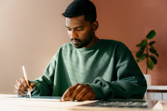 A man draws on a graphic tablet indoors