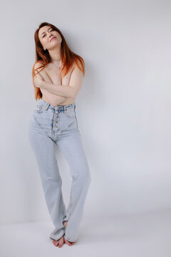 Full body studio portrait of redhead woman in blue jeans